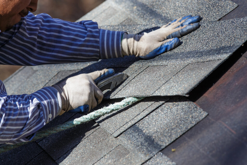 Skilled roofer cutting asphalt shingles by hand during detailed roofing in Bessemer City, NC.